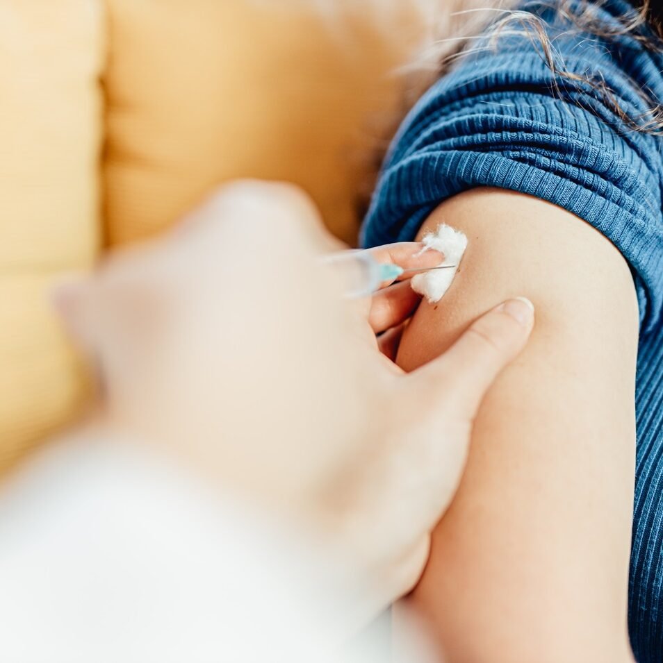 photo of a healthcare professional administering a vaccine injection into a person’s upper arm