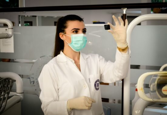 Clinician in mask and white coat looking at lab sample